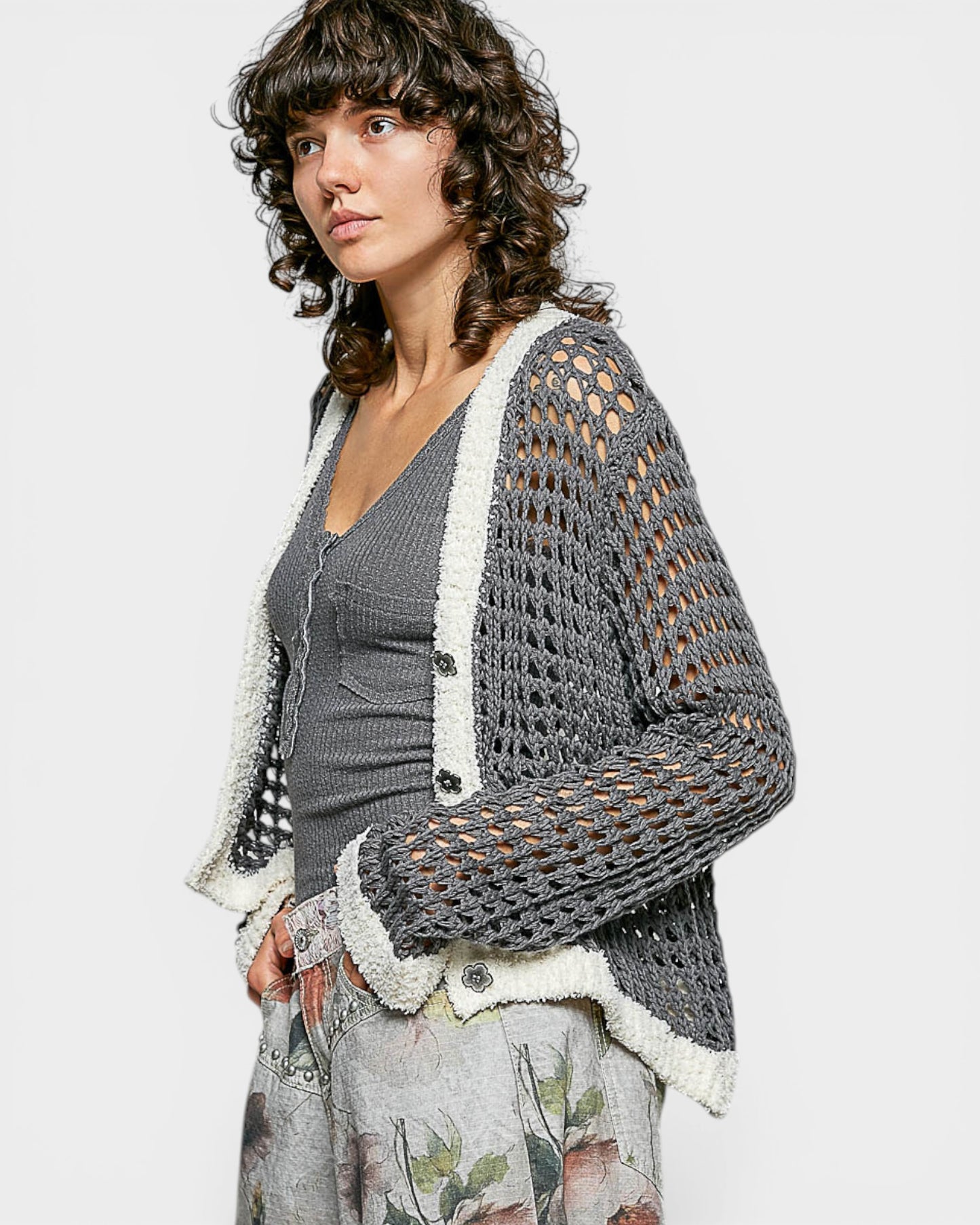Woman wearing a gray and white crochet cardigan on a light background