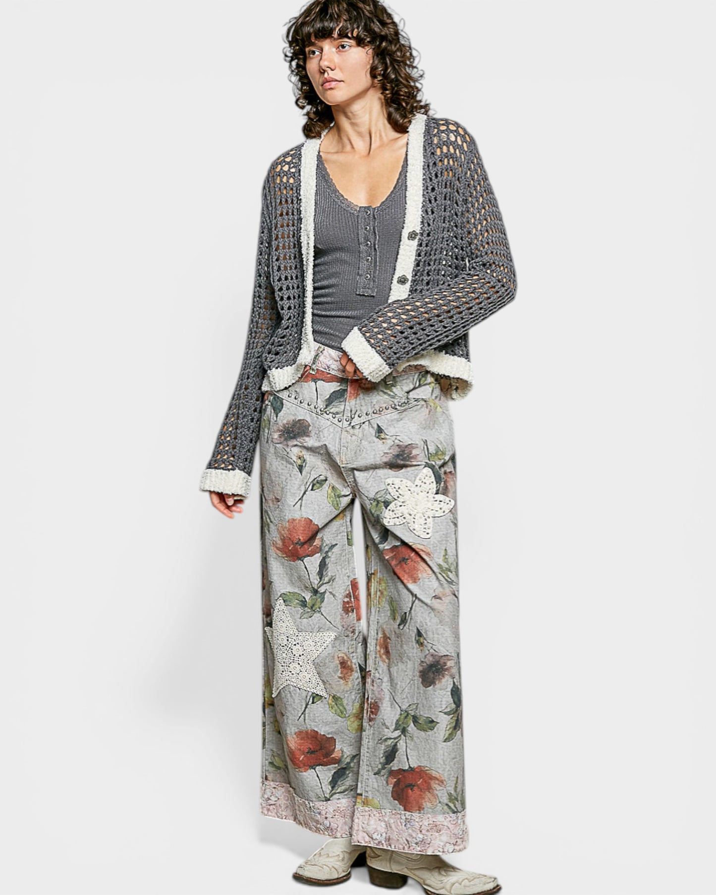 Woman wearing a patterned cardigan, gray top, and floral skirt on a white background