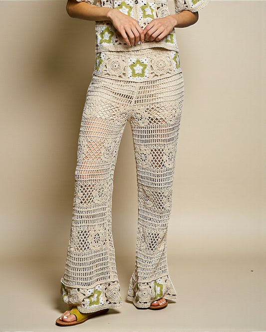 Person wearing a floral top and crochet pants on a plain background