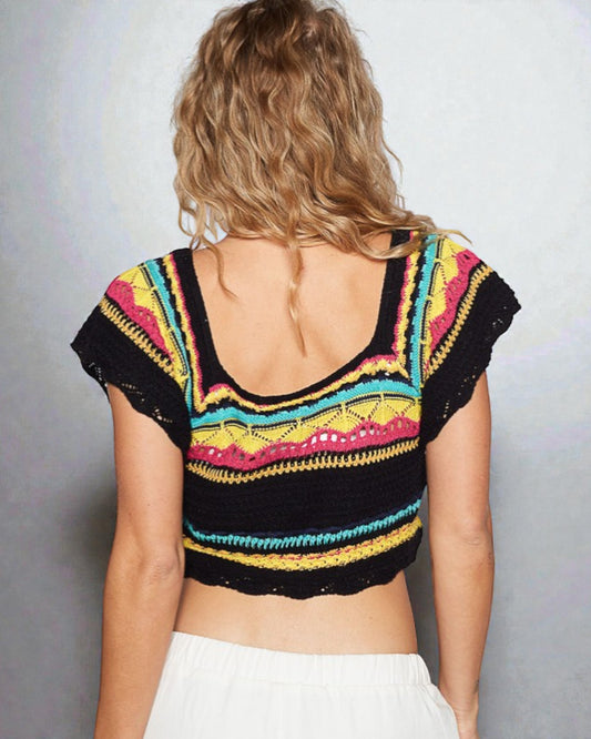 Woman wearing a colorful crochet top with a plain background