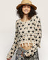 Woman wearing a floral crochet top and wide-brimmed hat on a plain background
