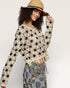 Woman wearing a floral crochet sweater and wide-brimmed hat on a plain background