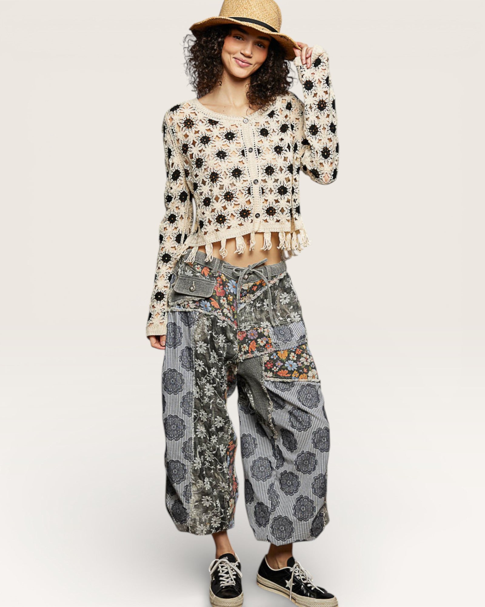 Woman wearing a floral sweater and patterned pants on a white background