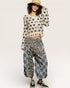 Woman wearing a floral sweater and patterned pants on a white background