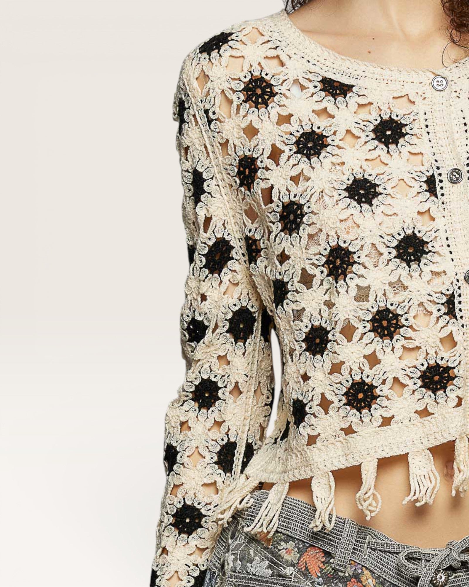 Crocheted top with black floral patterns on a neutral background