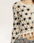 Crocheted top with black floral patterns on a neutral background