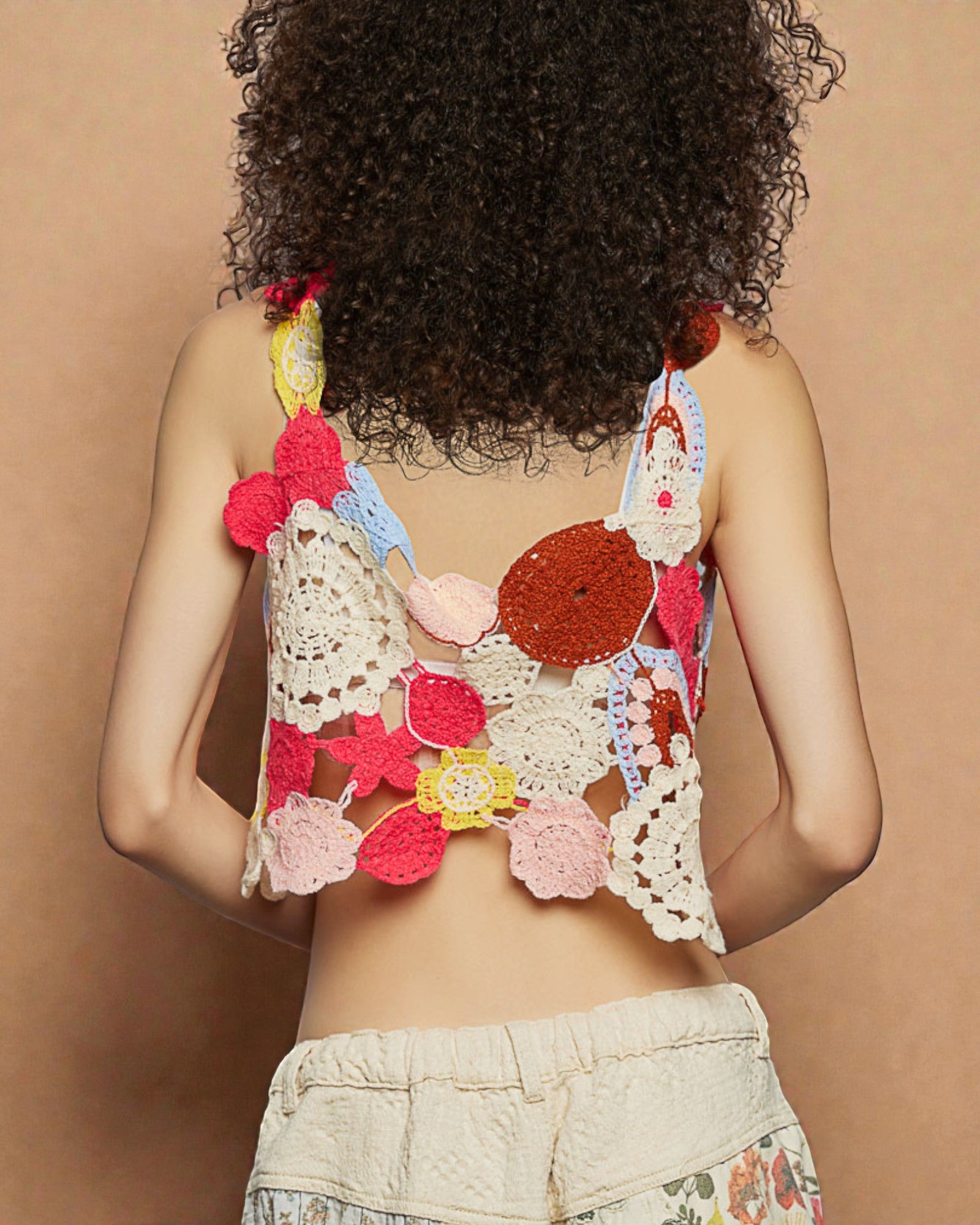 Person wearing a colorful, crochet-style top against a beige background