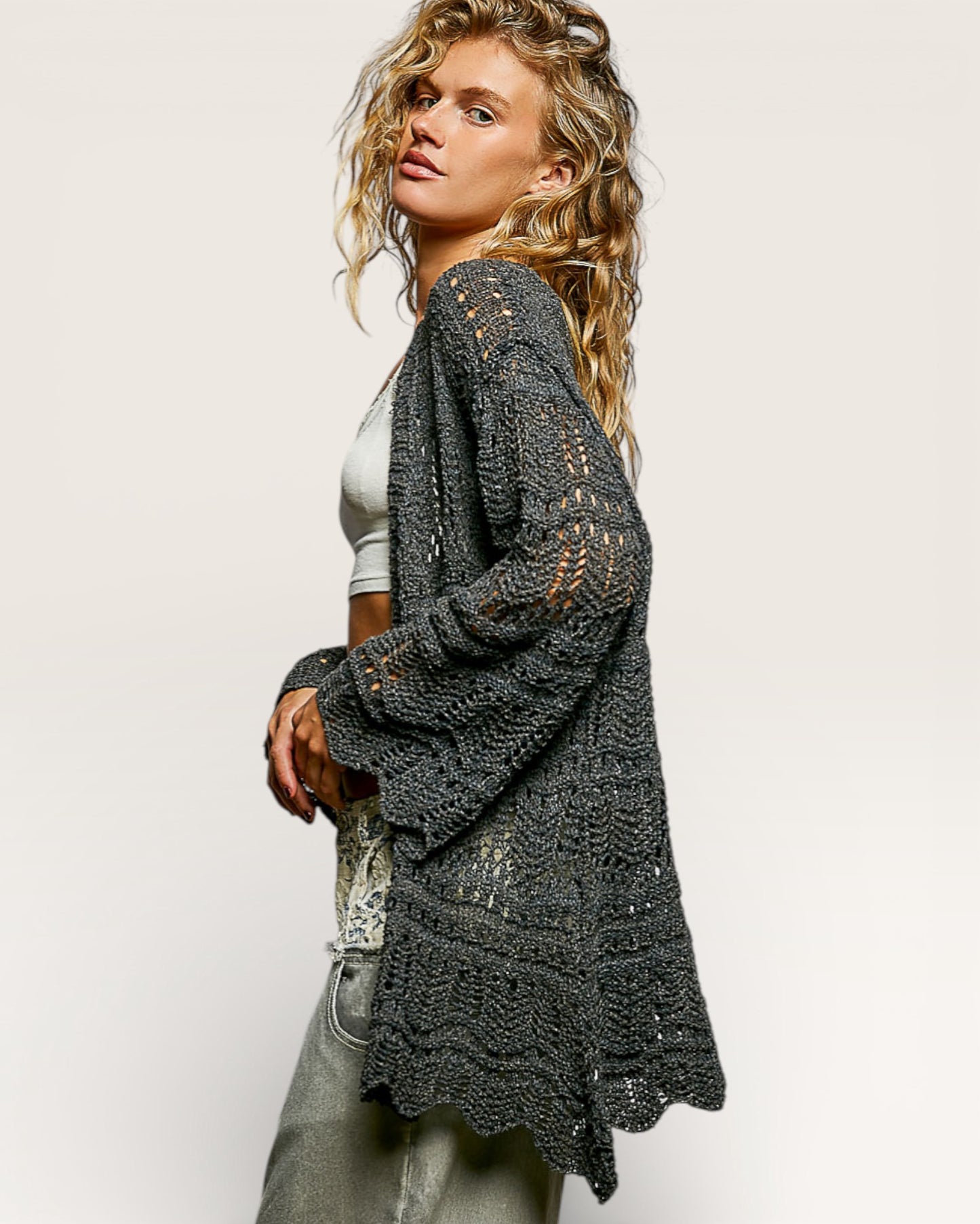 Woman wearing a dark gray crochet cardigan on a plain background