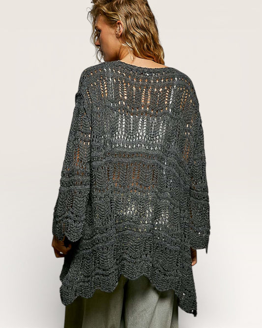 Person wearing a dark gray crochet poncho on a white background