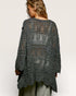 Person wearing a dark gray crochet poncho on a white background