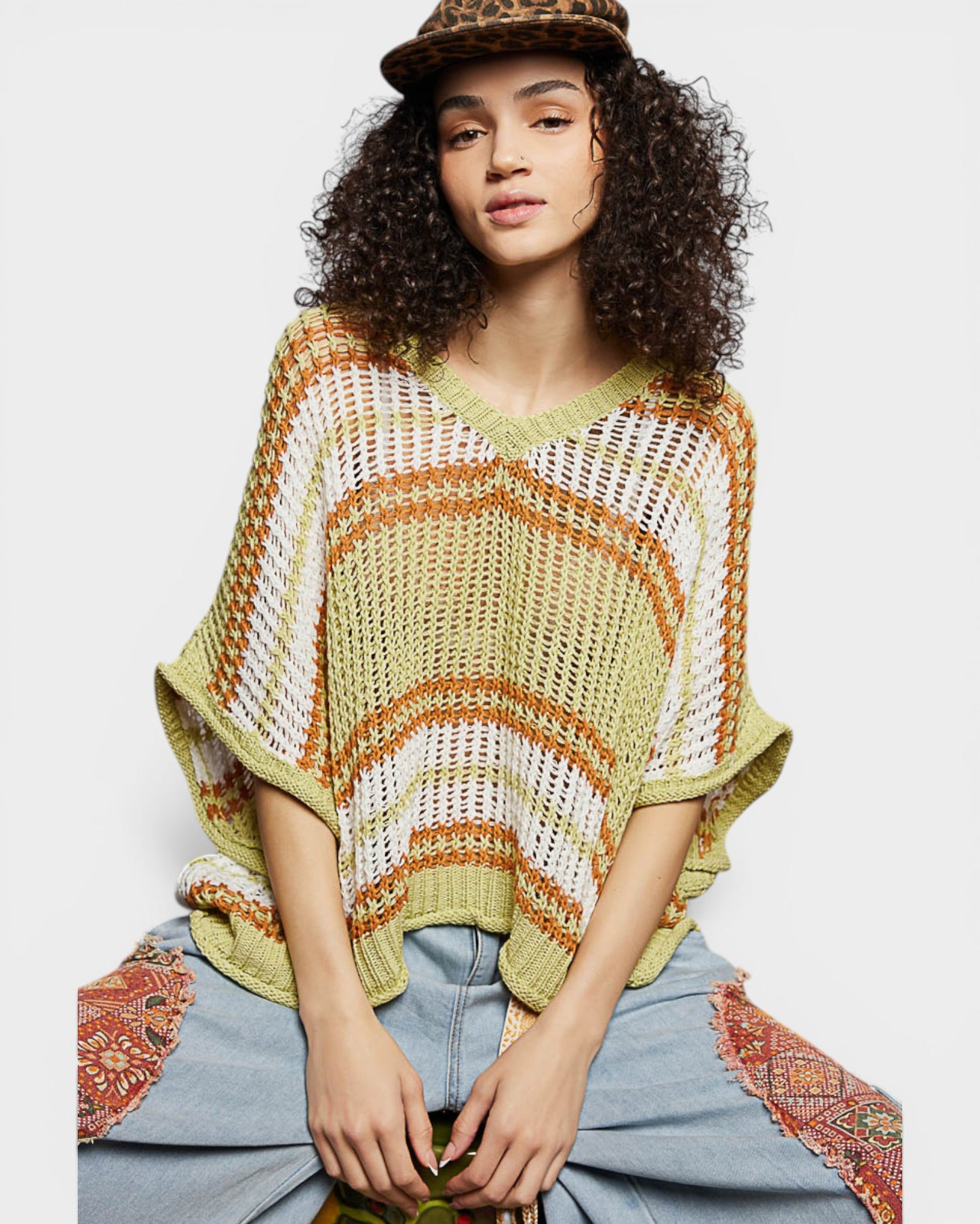 Woman wearing a colorful knitted poncho with a plain background