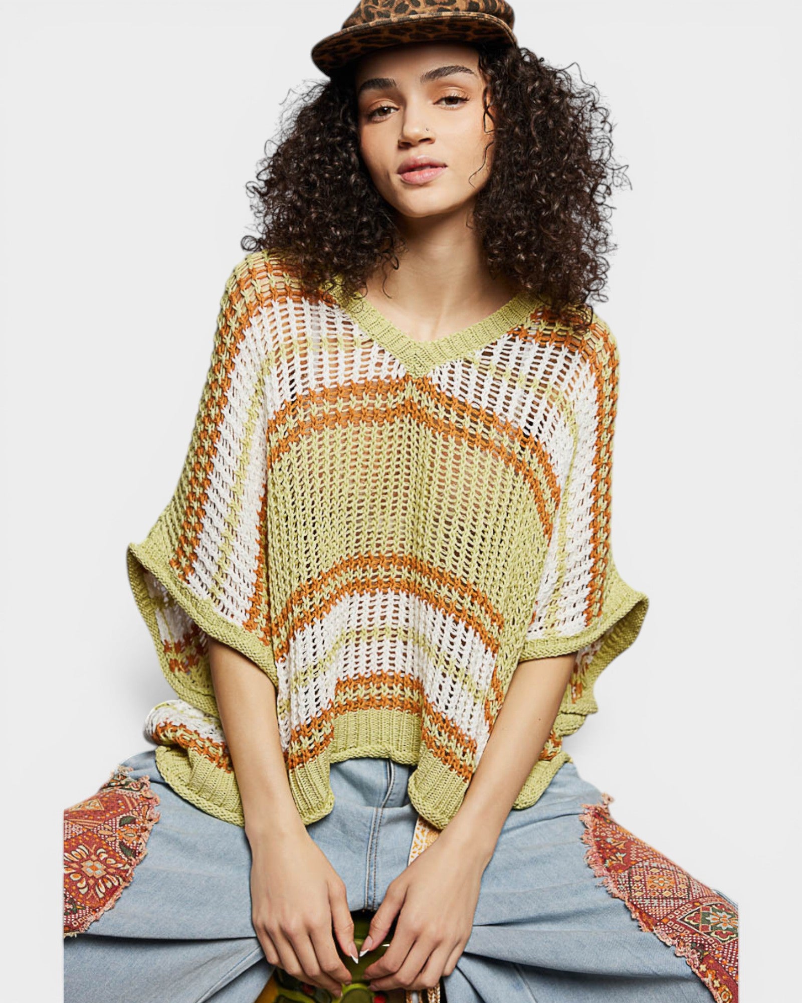 Woman wearing a colorful knitted poncho with a plain background