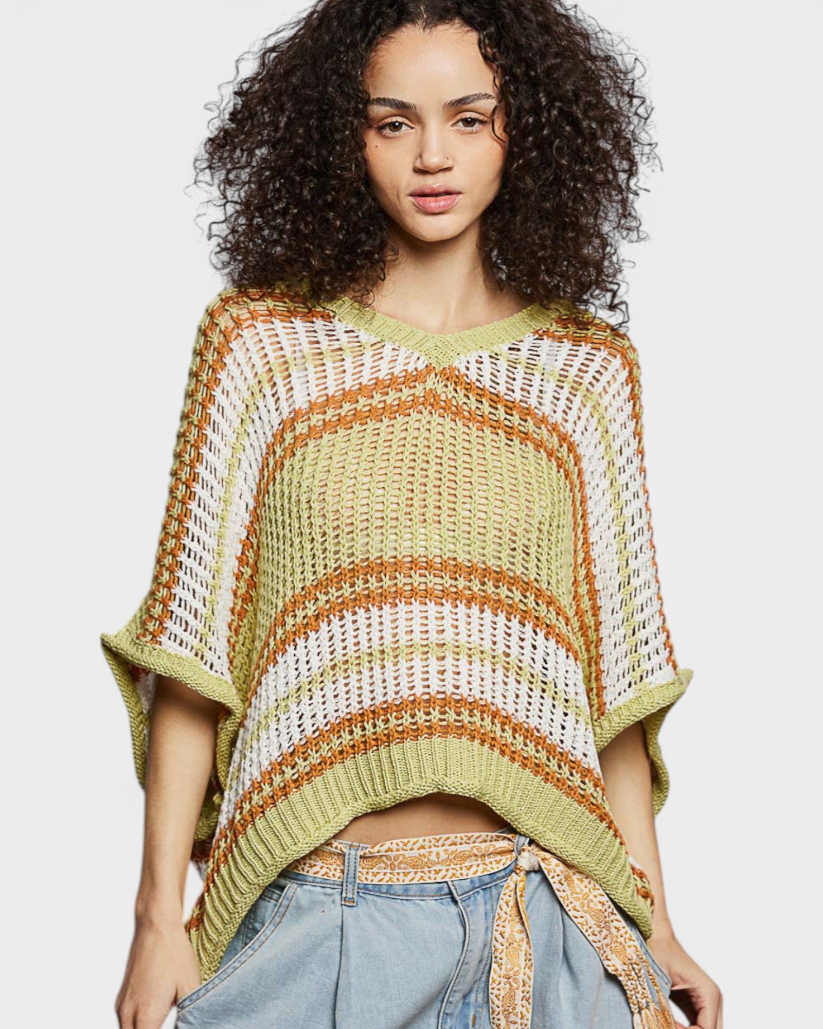 Woman wearing a colorful knitted poncho against a plain background