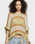 Woman wearing a colorful knitted poncho against a plain background