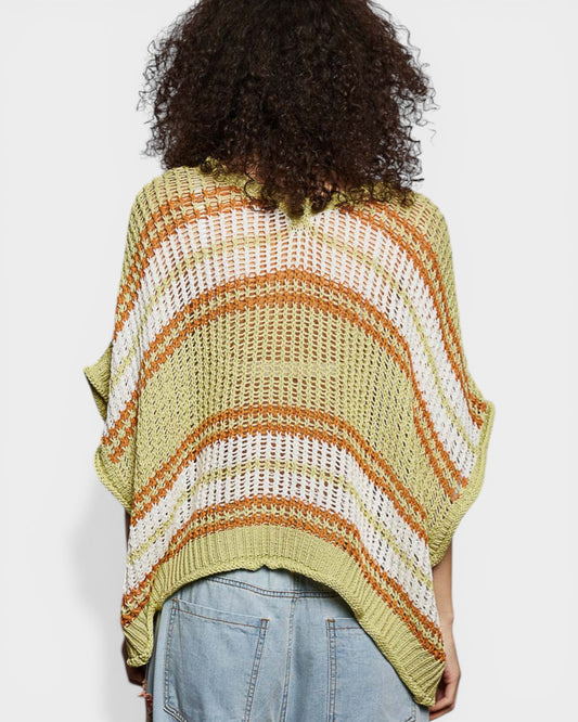 Person wearing a colorful striped poncho on a plain background