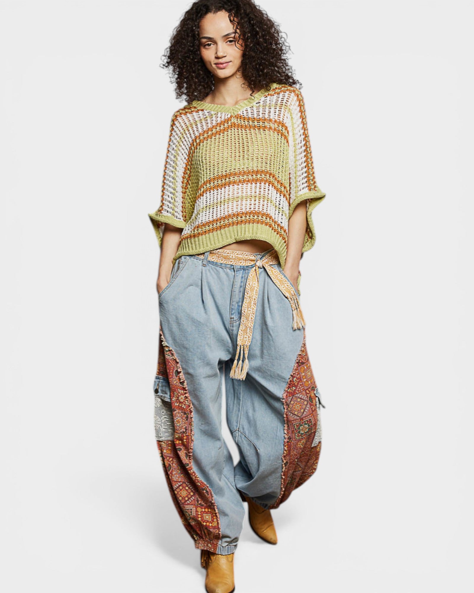 Woman wearing a colorful poncho and patterned pants on a white background
