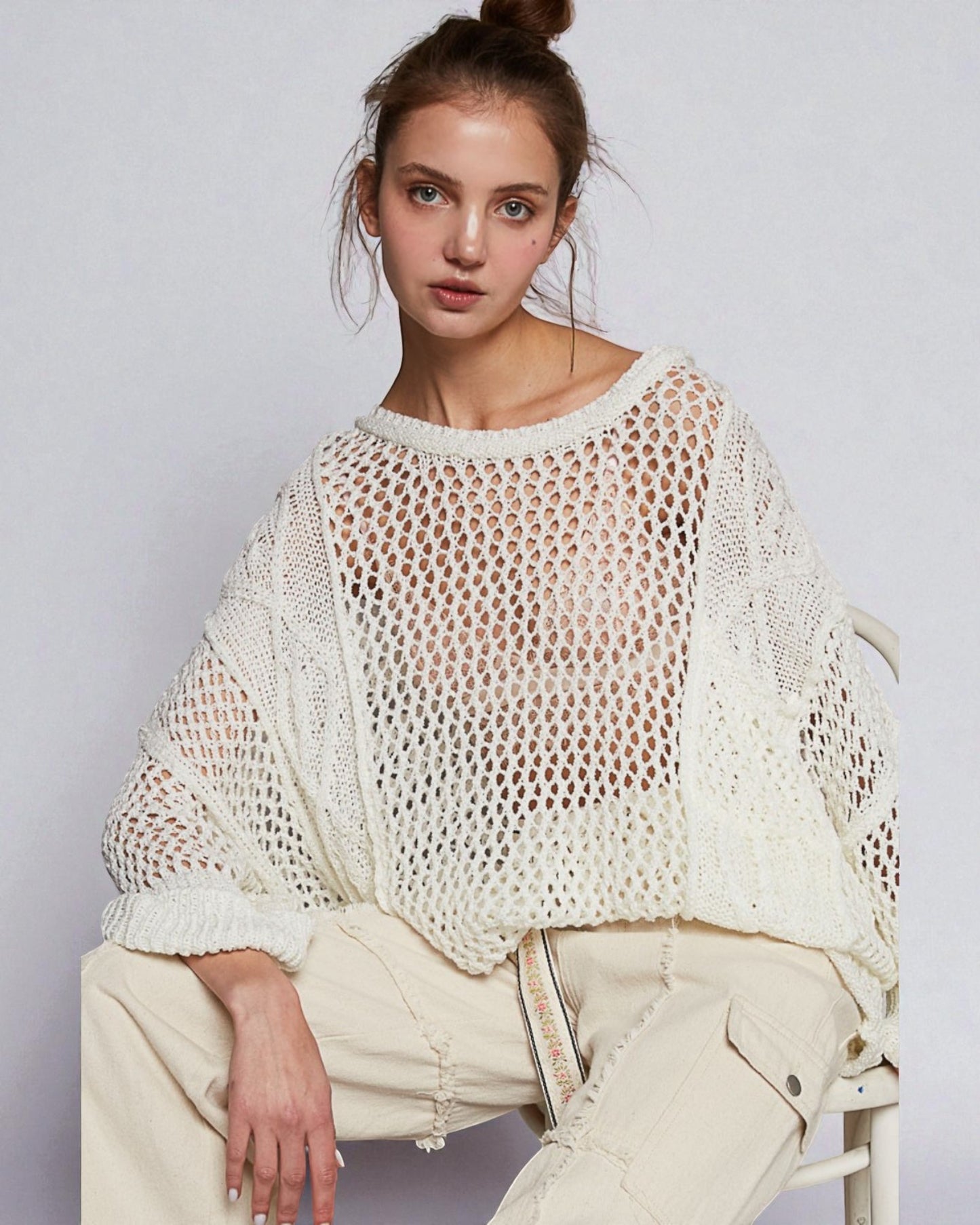 Woman wearing a white knit sweater against a plain background