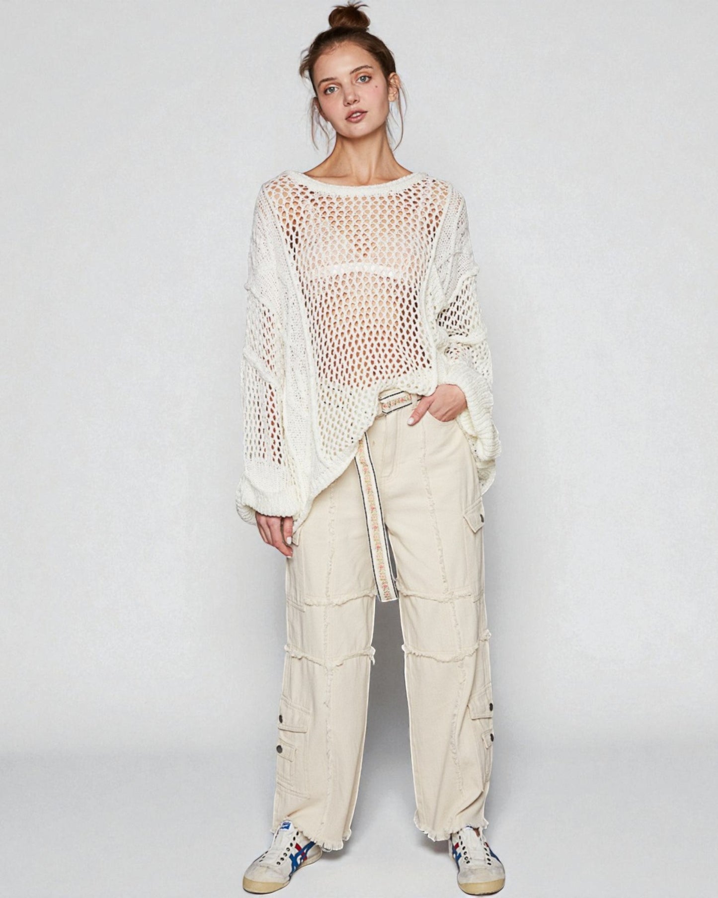 Person wearing a white crochet top and beige cargo pants on a plain background