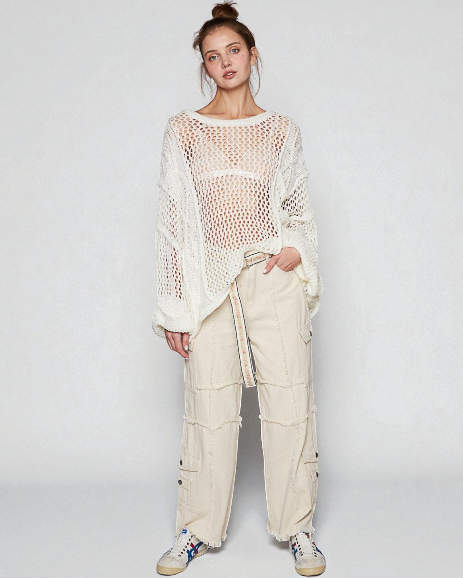 Person wearing a white crochet top and beige cargo pants on a plain background