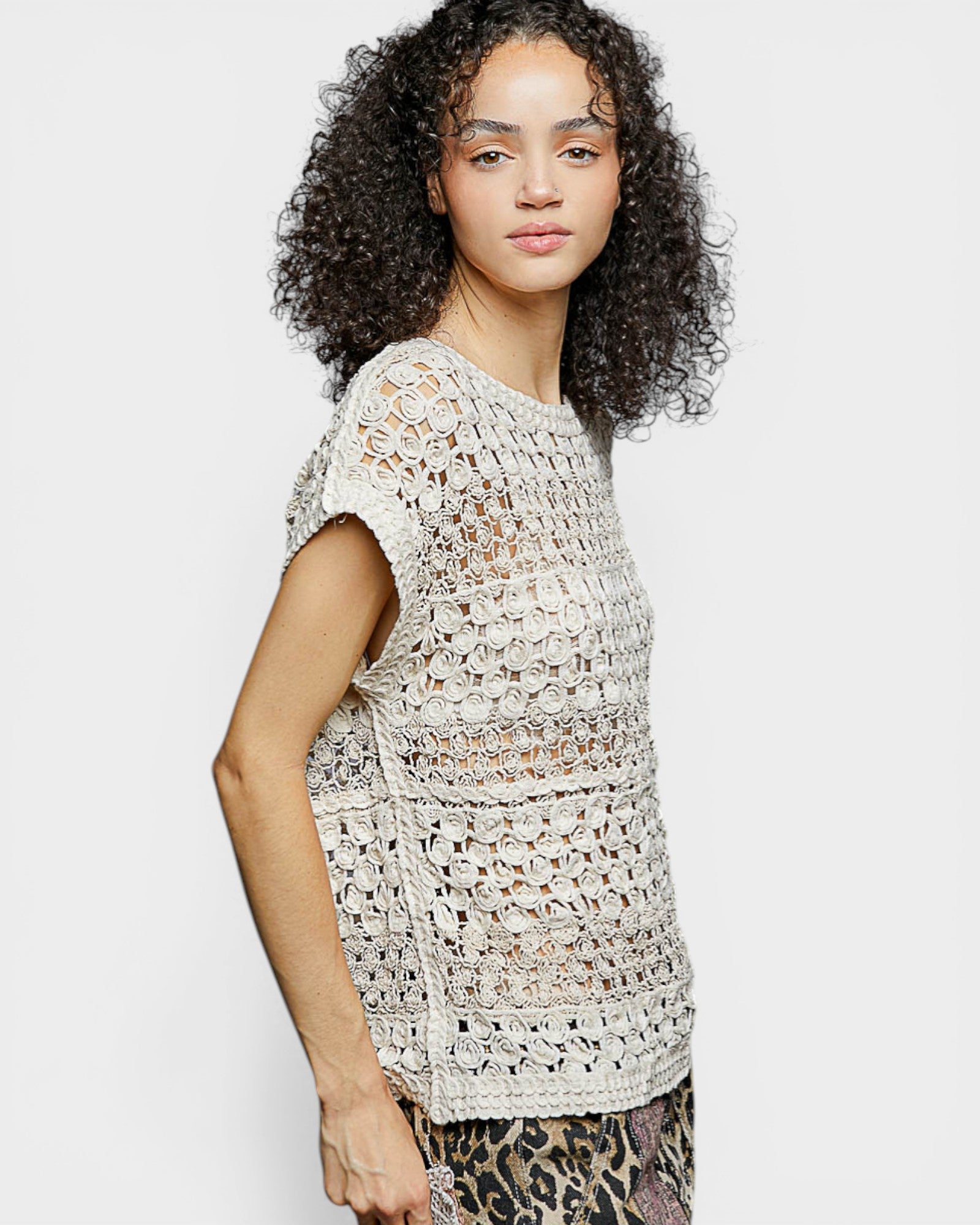 Woman wearing a crochet top on a plain background
