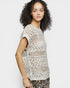 Woman wearing a crochet top on a plain background