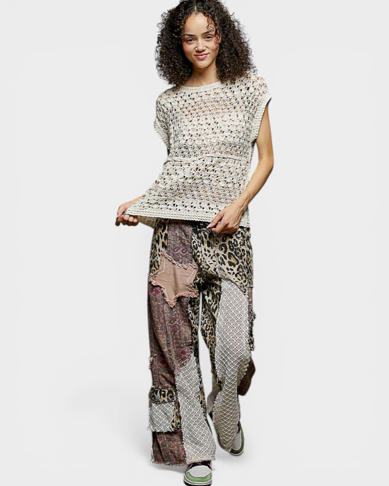 Woman wearing a patterned top and patchwork pants on a white background