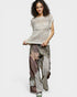 Woman wearing a patterned top and patchwork pants on a white background