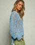 Woman wearing a light blue knitted sweater against a neutral background