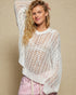 Woman wearing a white crochet top against a beige background