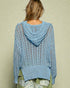 Light blue knitted sweater with a hood worn by a person on a beige background