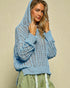 Woman wearing a blue crochet sweater against a beige background