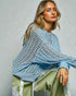 Woman wearing a blue knitted poncho against a plain background