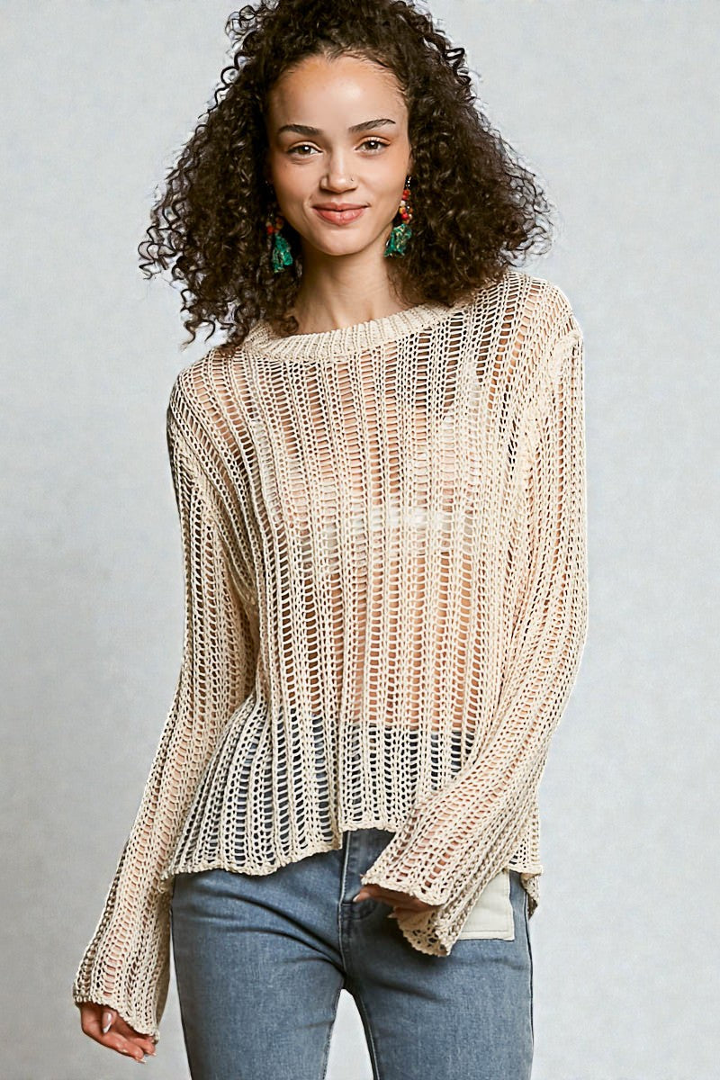 Woman wearing a beige knitted sweater and blue jeans against a gray background