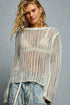 Woman wearing a textured knit sweater and jeans against a gray background