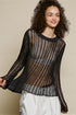 Woman wearing a black knit top with a beige background