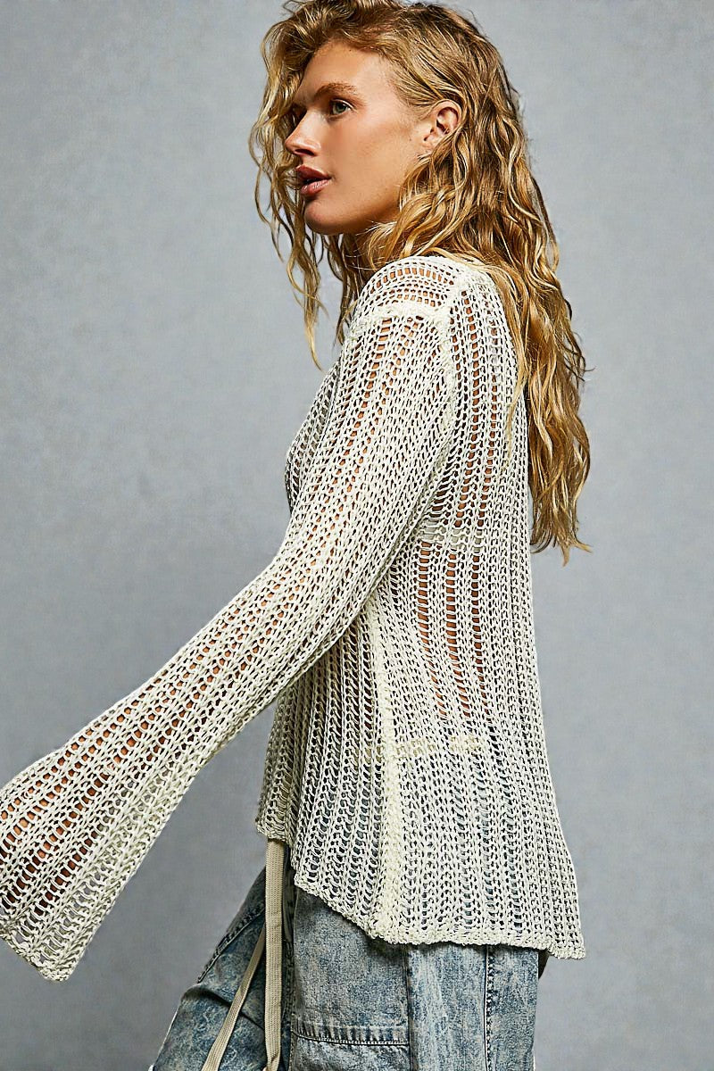 Woman wearing a knitted cardigan and jeans against a gray background