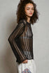 Woman wearing a black and gold patterned sweater against a plain background