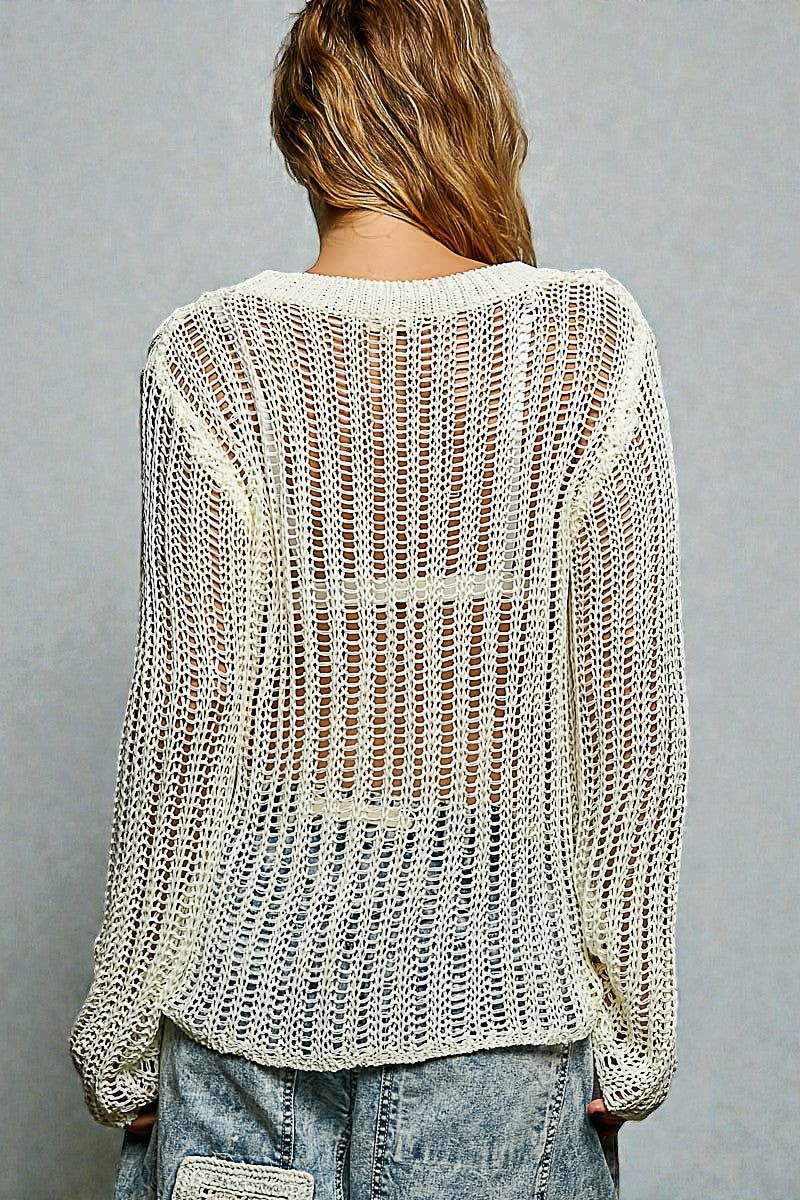 Person wearing a light-colored knit sweater and jeans on a gray background