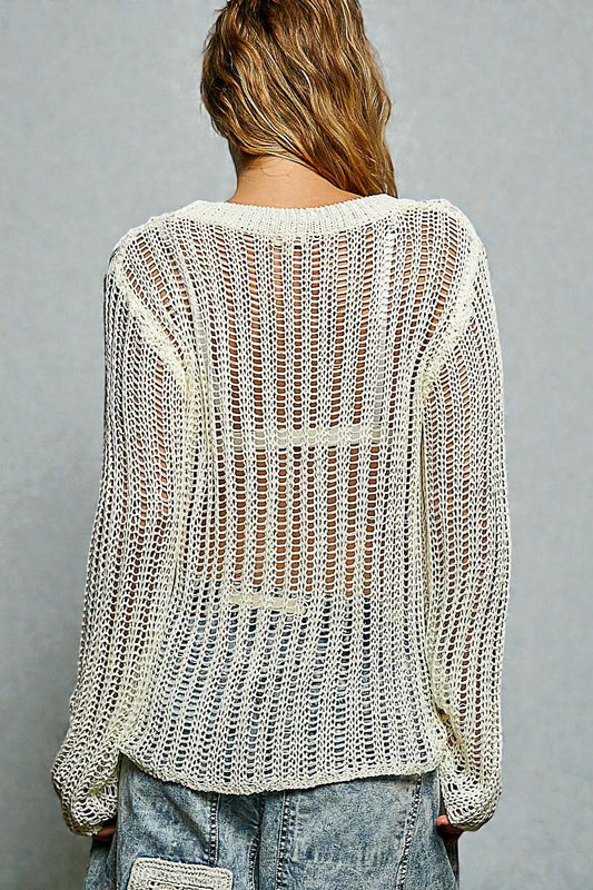 Person wearing a light-colored knit sweater and jeans on a gray background