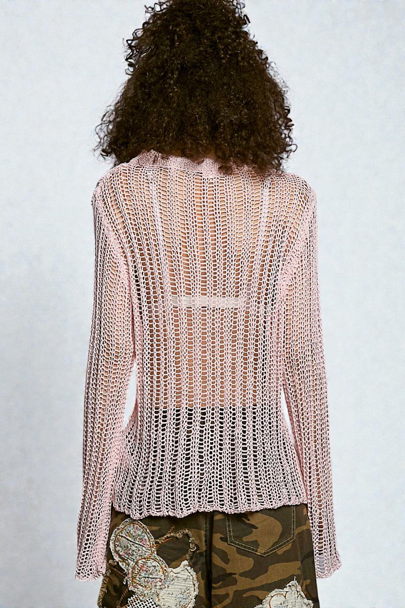 Person wearing a light pink knit cardigan on a plain background