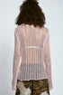 Person wearing a light pink knit cardigan on a plain background