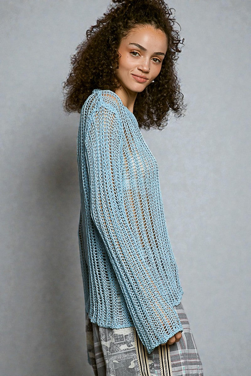Woman wearing a light blue knitted sweater against a gray background