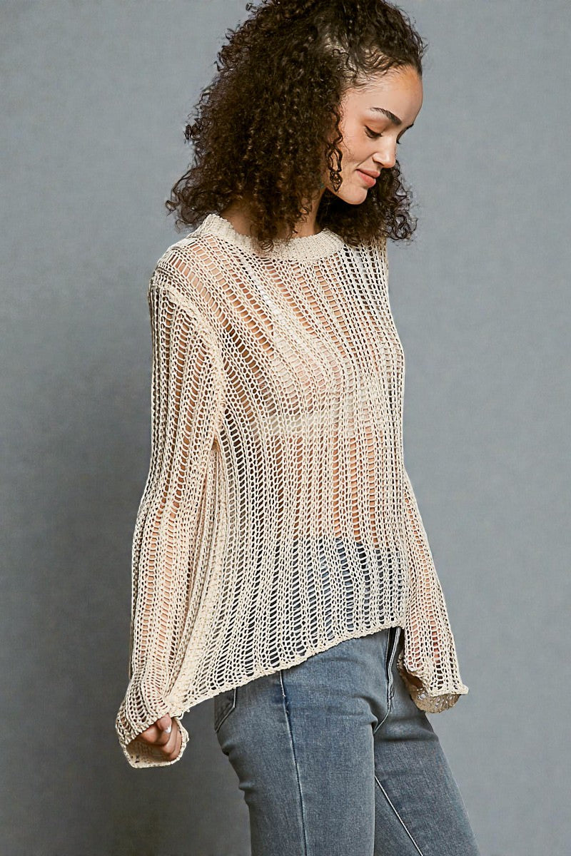 Woman wearing a beige knitted sweater against a gray background