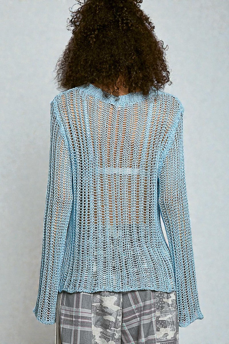 Person wearing a light blue knitted cardigan against a plain background