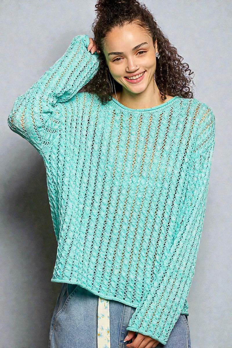 Woman wearing a light blue knitted sweater against a gray background