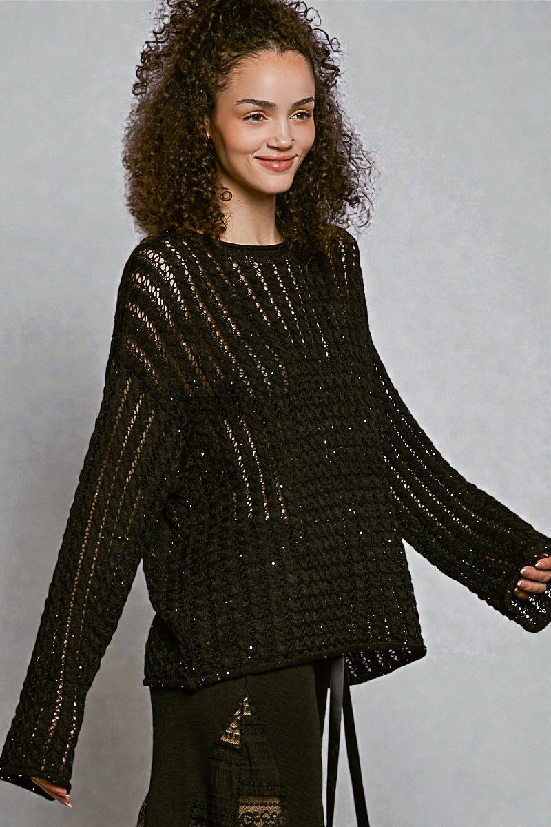 Woman wearing a black textured sweater against a gray background