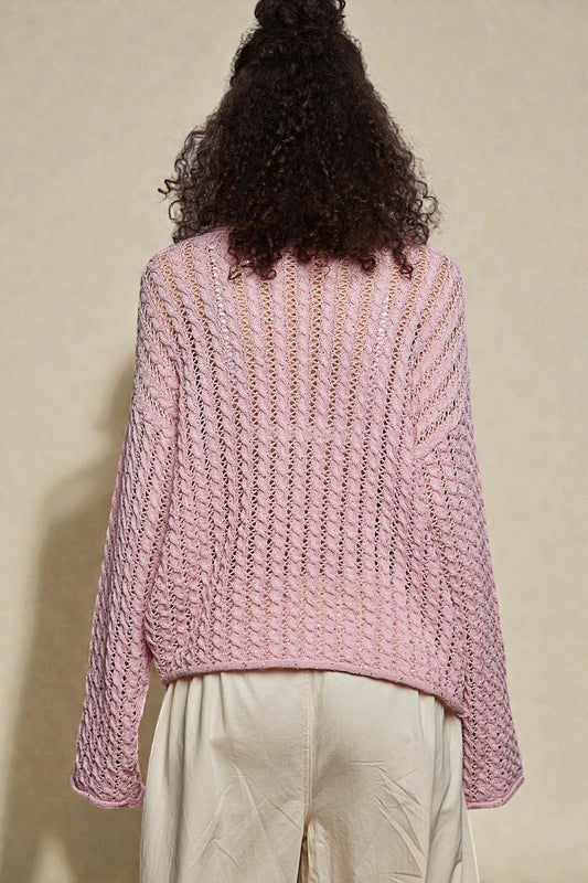 Person wearing a pink knitted sweater against a beige background