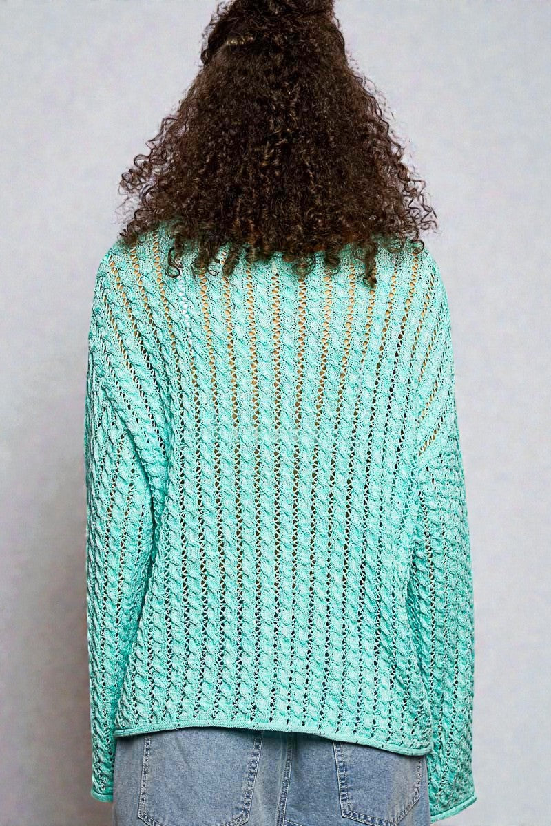 Person wearing a teal knitted sweater with a plain background