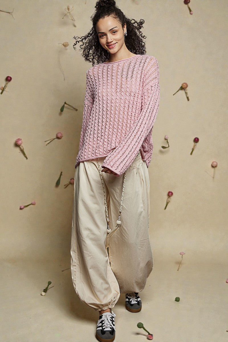 Woman wearing a pink knitted sweater and beige pants against a beige background with decorative elements.