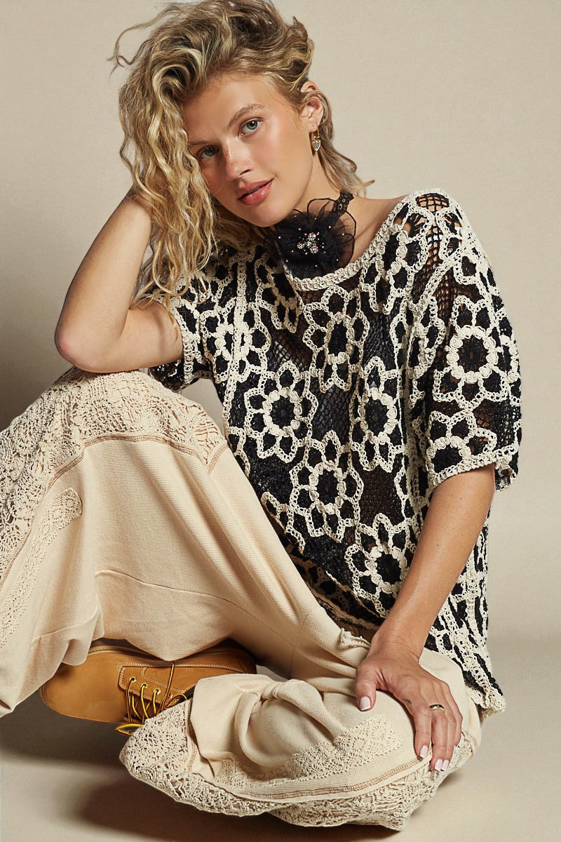 Woman wearing a black and white patterned top sitting on a beige surface.